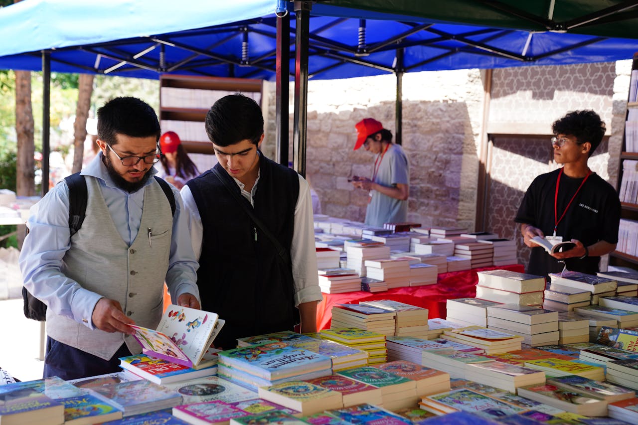 People browsing books at an outdoor book fair. Diverse selection and engaged readers.
