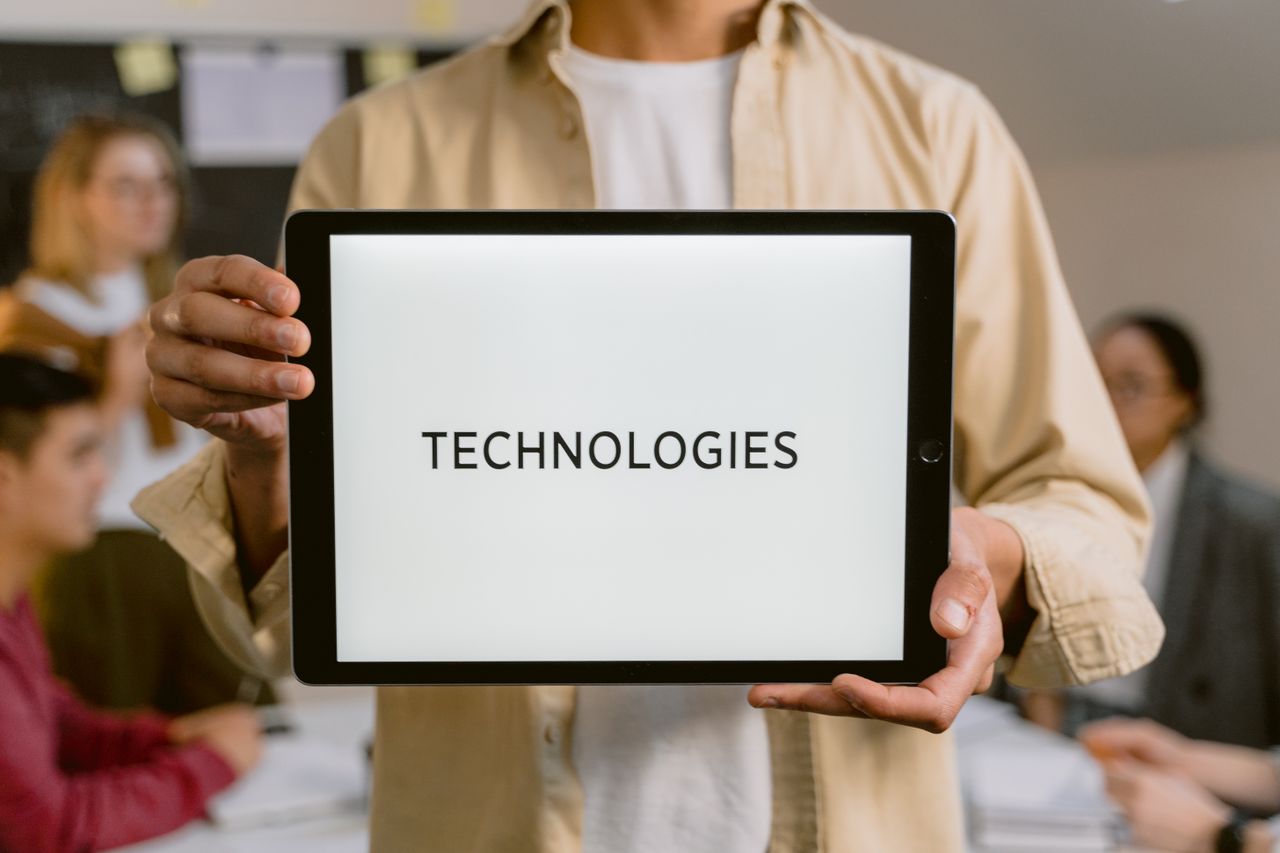 Business professionals discussing technologies, shown on a tablet in an office setting.